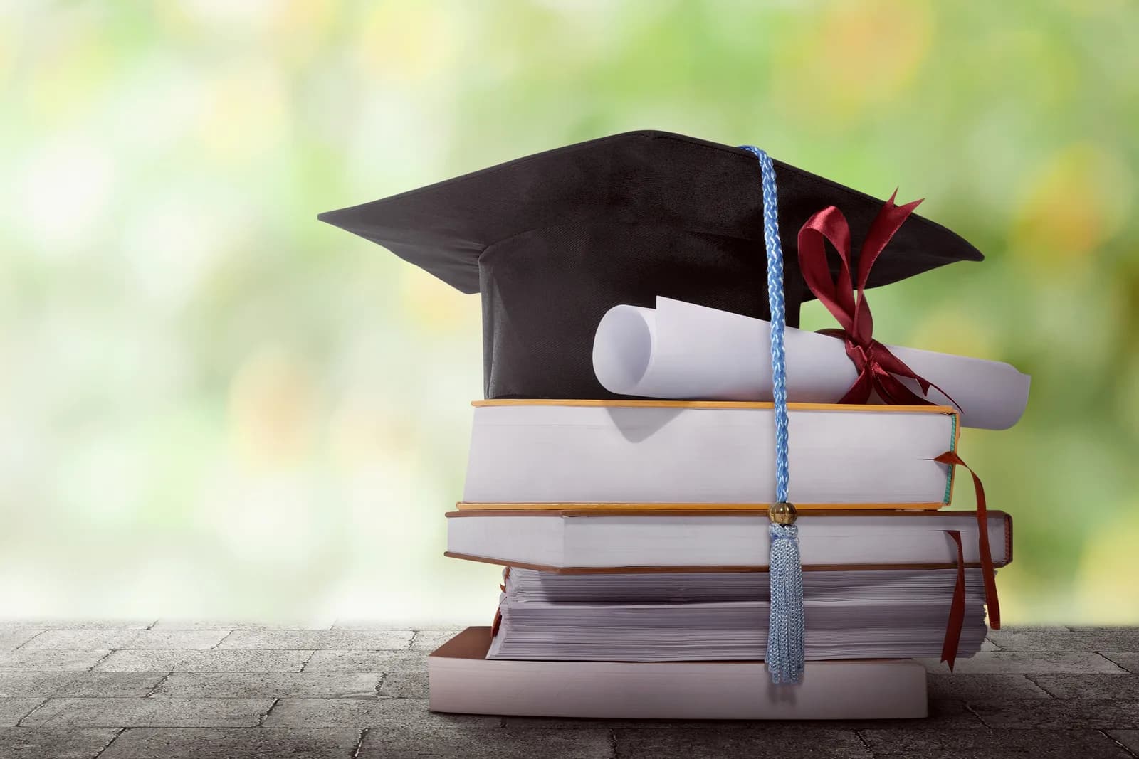 A graduation cap and a rolled diploma resting on a stack of books